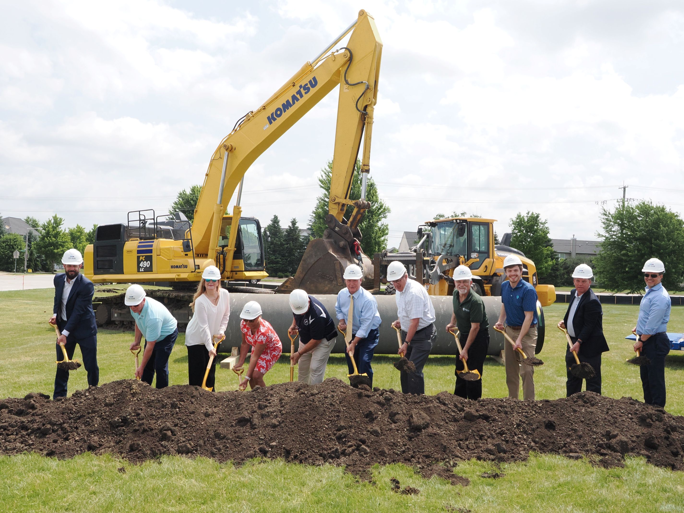 11 people with shovels and hard hats in front of excavator at Waterlink Groundbreaking